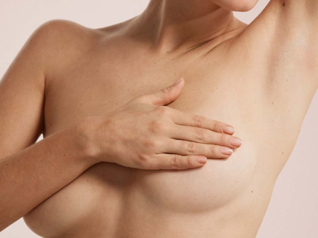 Mulher sorridente e com postura reta, vestindo uma blusa leve, demonstrando o alívio das dores nas costas e o conforto estético após a cirurgia de Mamoplastia Redutora na Clínica Orvia.