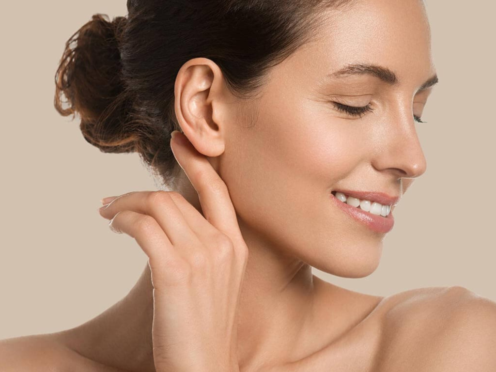 Mulher sorridente de perfil com os cabelos presos em um coque, exibindo orelhas harmoniosas e proporcionais, representando a liberdade e a autoconfiança após a cirurgia de Otoplastia na Clínica Orvia.